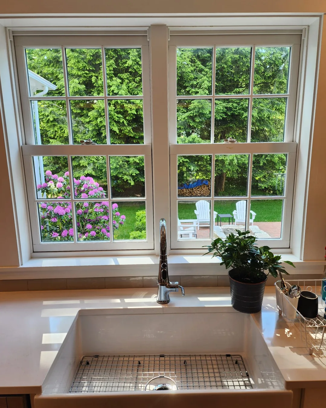 Clean kitchen sink and bright windows overlooking a green backyard