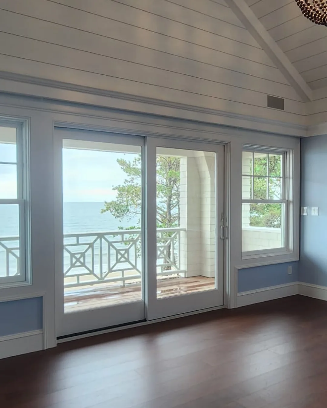 Clean, empty coastal room with gleaming floors and a view of the water